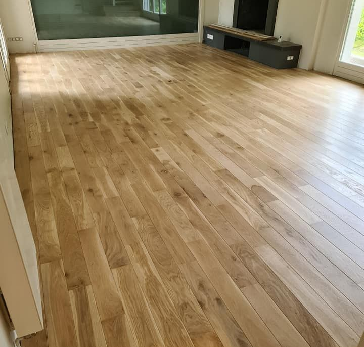 Une pièce vide et lumineuse avec un parquet en bois clair.