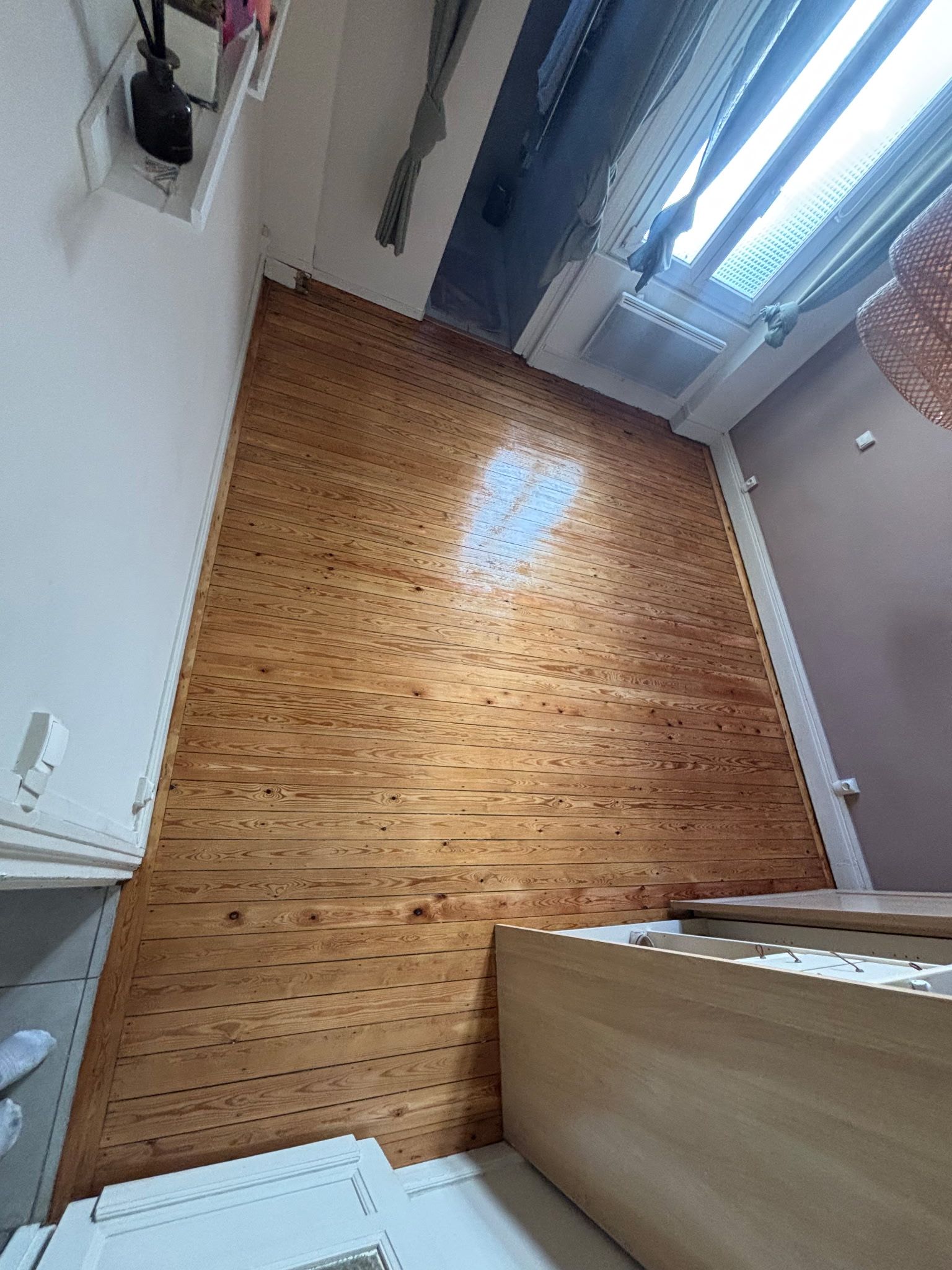 Une chambre vide avec un parquet massif au sol, poncé et vitrifié.