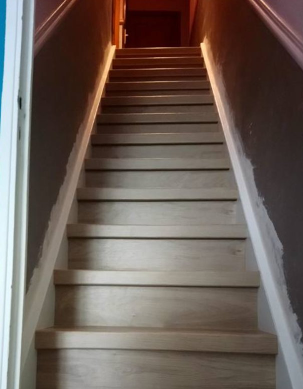 Un escalier intérieur étroit aux marches en bois clair.