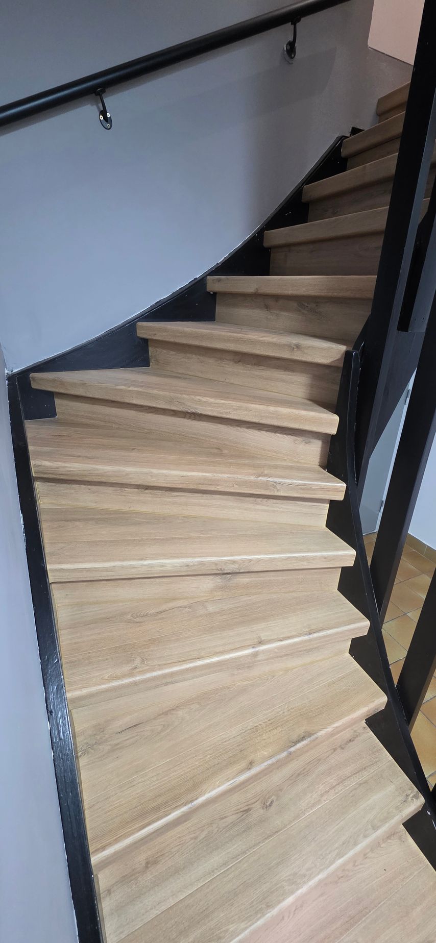 Un escalier intérieur avec des marches en bois clair et une rampe en métal.