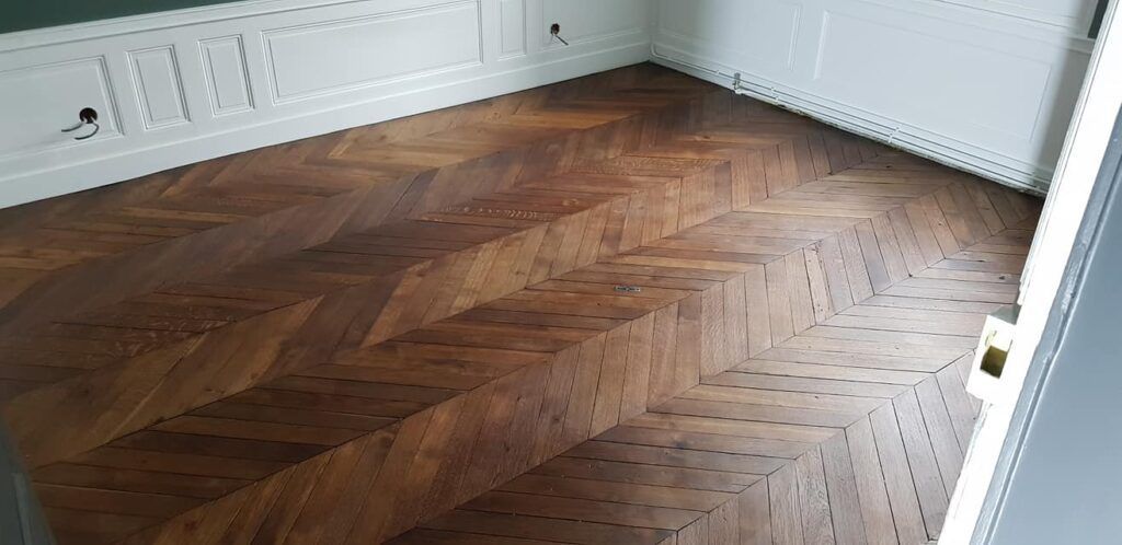 Une pièce vide avec un parquet massif au sol, au bois foncé.