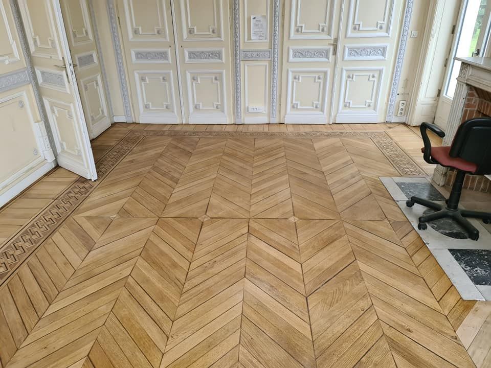 Un parquet à chevrons orné dans une pièce lumineuse avec des murs à panneaux.