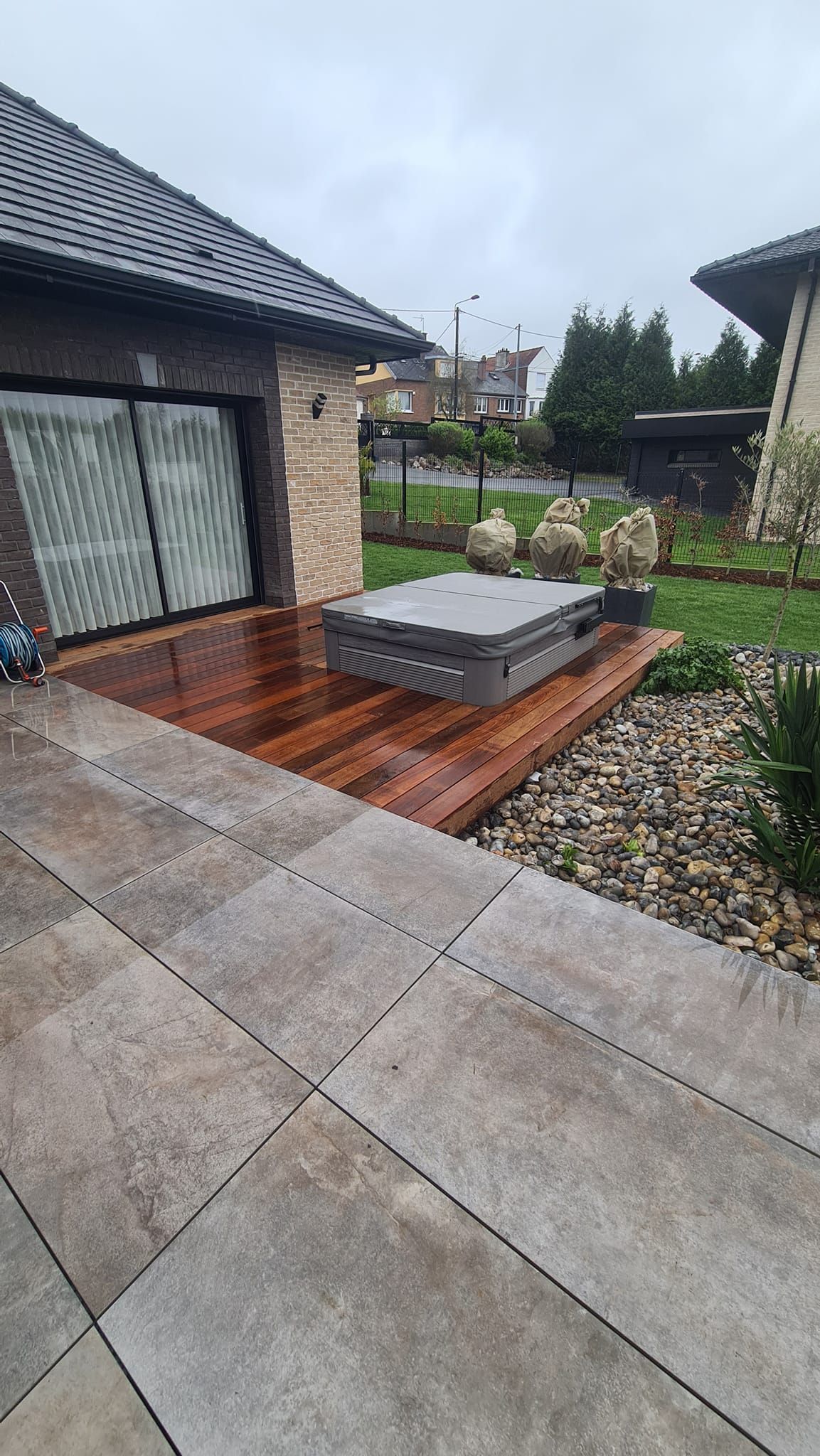 Une terrasse de maison, partiellement carrelée et partiellement en bois, avec un jacuzzi.