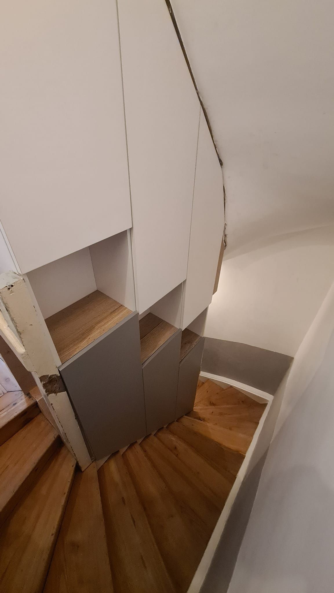 Des escaliers en bois avec des rangements intégrés au mur.