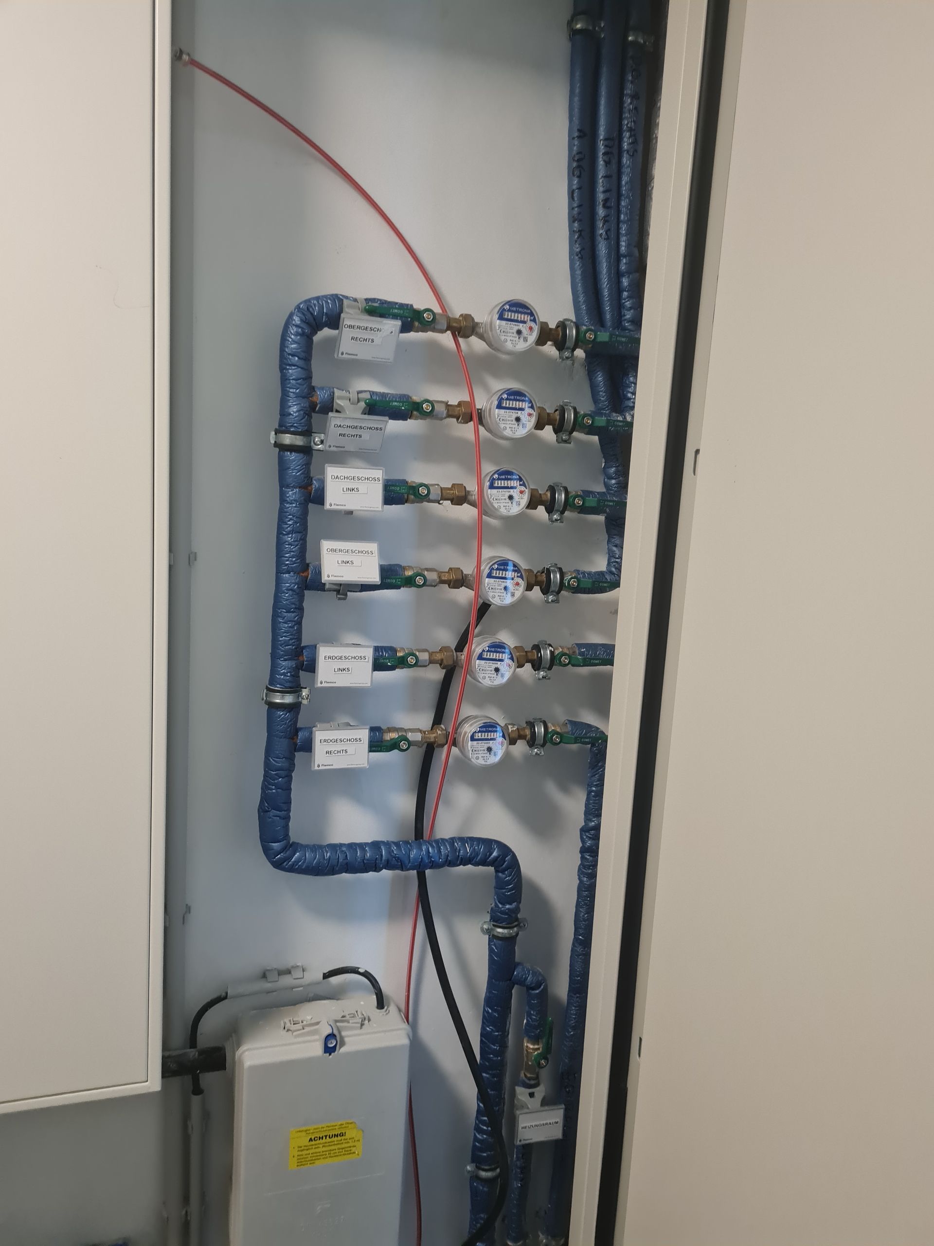 In einem Raum sind mehrere Rohre an einer Wand angeschlossen.