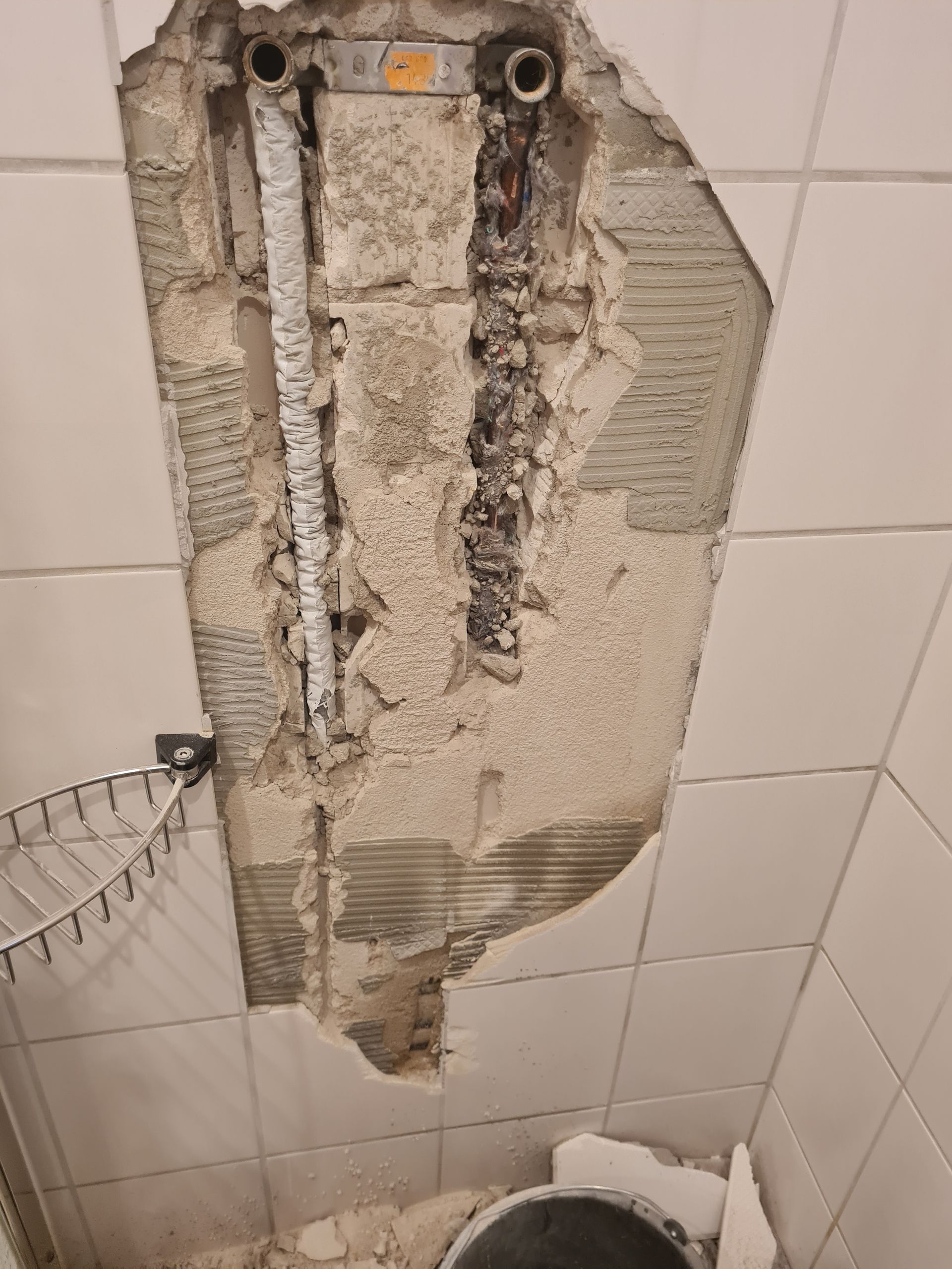 Ein Loch in der Wand eines Badezimmers, aus dem ein Rohr herauskommt.