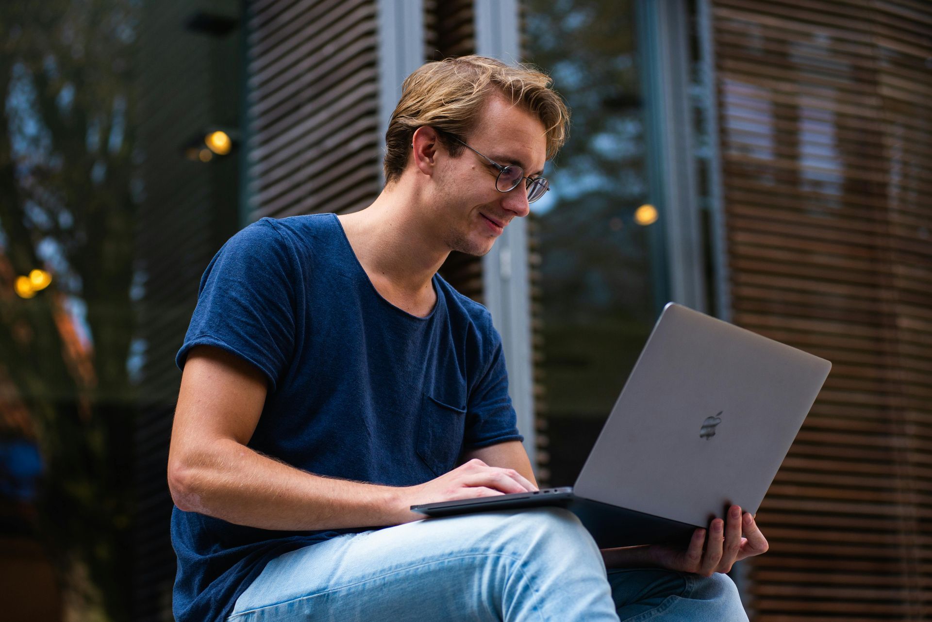 Ein Mann sitzt auf einer Veranda und benutzt einen Laptop.