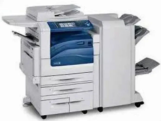 A white and blue printer is sitting on top of a white table.