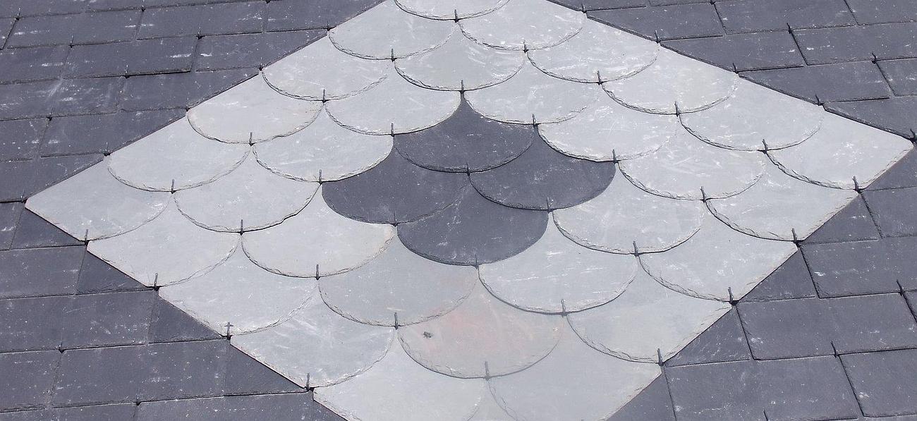 Pavé à motif de losanges gris, avec des carreaux gris clair en forme de coquille Saint Jacques entourés de briques gris.