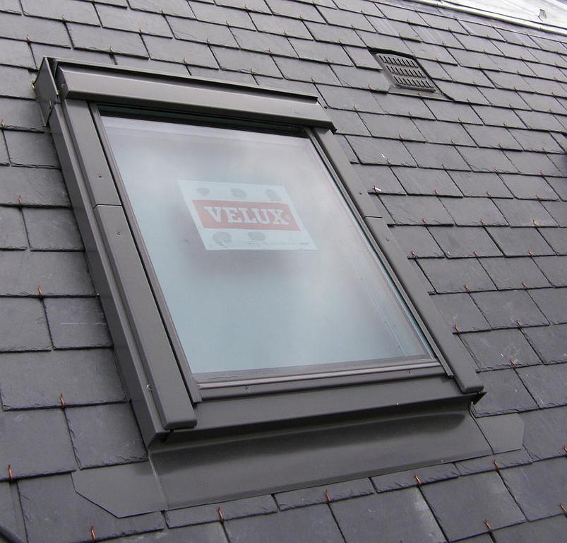 Un puits de lumière VELUX installé dans un toit en ardoise foncée.