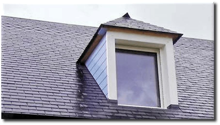 Lucarne sur un toit en bardeaux gris; garniture blanche autour de la fenêtre, revêtement bleu-gris.