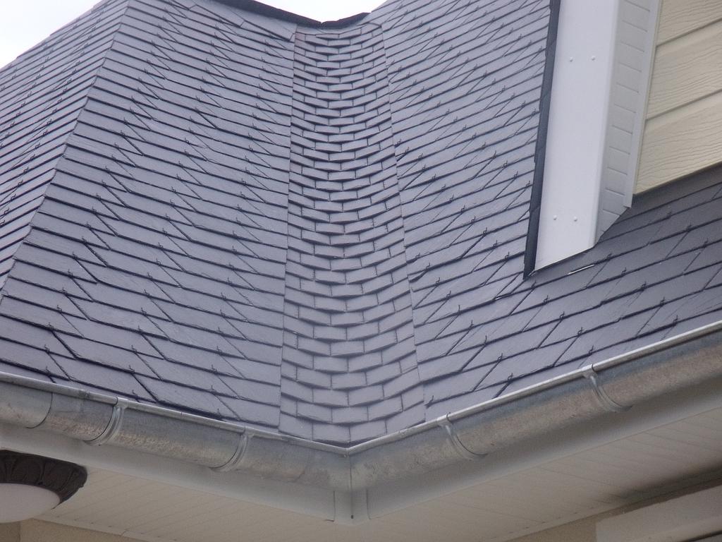 Toiture en ardoise grise avec gouttière et angle, vue en angle.