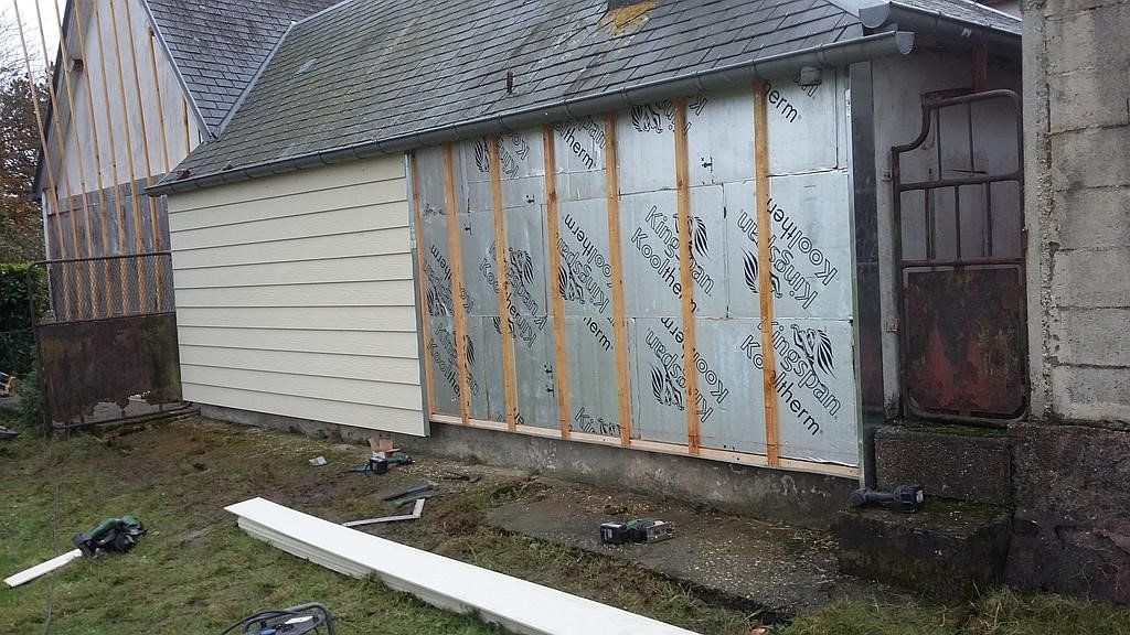 Extérieur du garage avec isolation et poutres en bois, construction en cours.