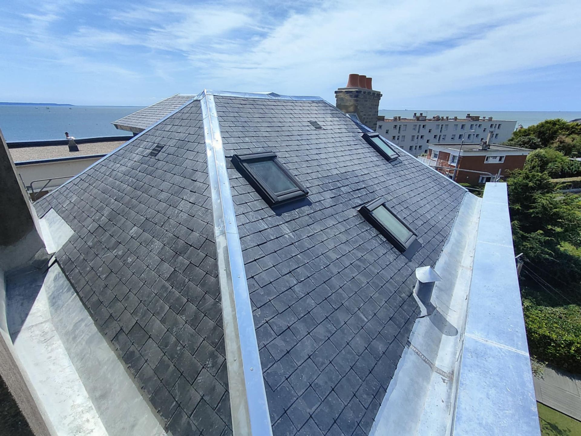 Un puits de lumière ouvert dans un toit en bardeaux bruns.