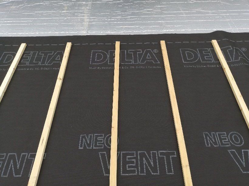 Sous-couche de toiture noire avec lattes verticales en bois, prête pour la pose de la toiture.