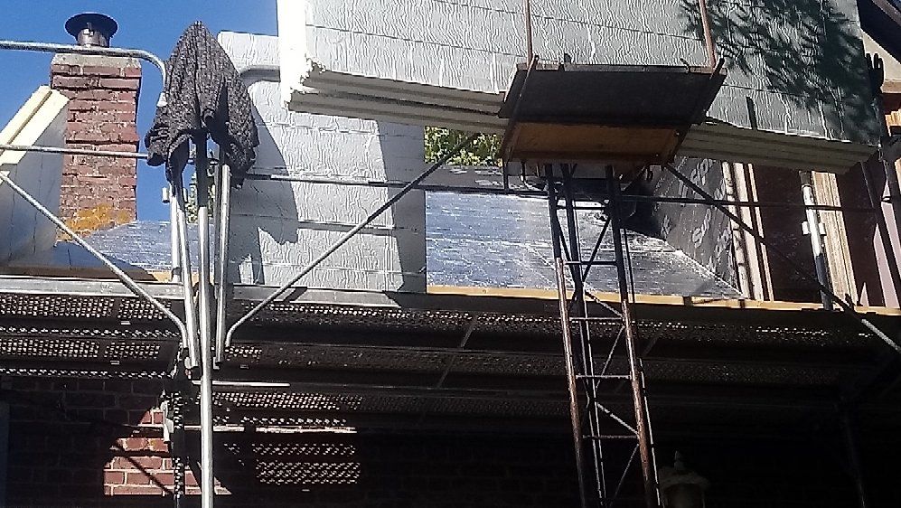 Chantier : échafaudage, réfection de murs avec isolation. Cheminée en briques à gauche.