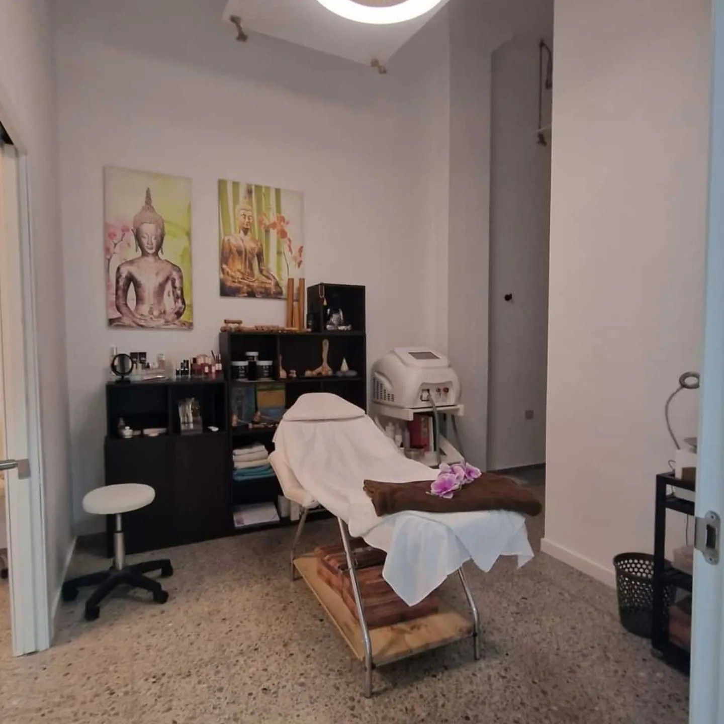 Una sala de tratamientos de spa con mesa de masajes, arte de Buda y equipo médico.