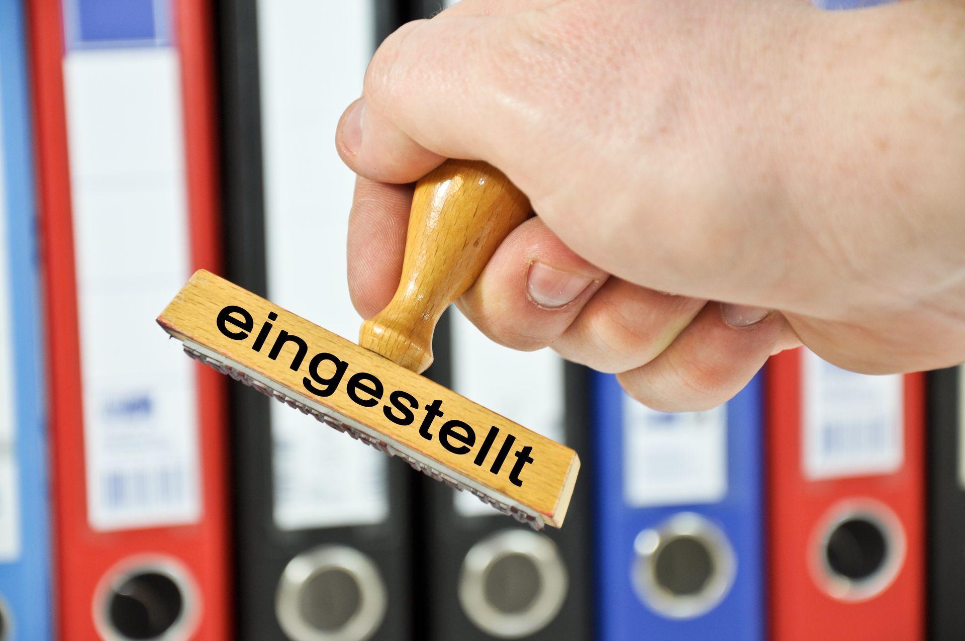 Eine Person hält einen Stempel mit der Aufschrift „eingestellt“