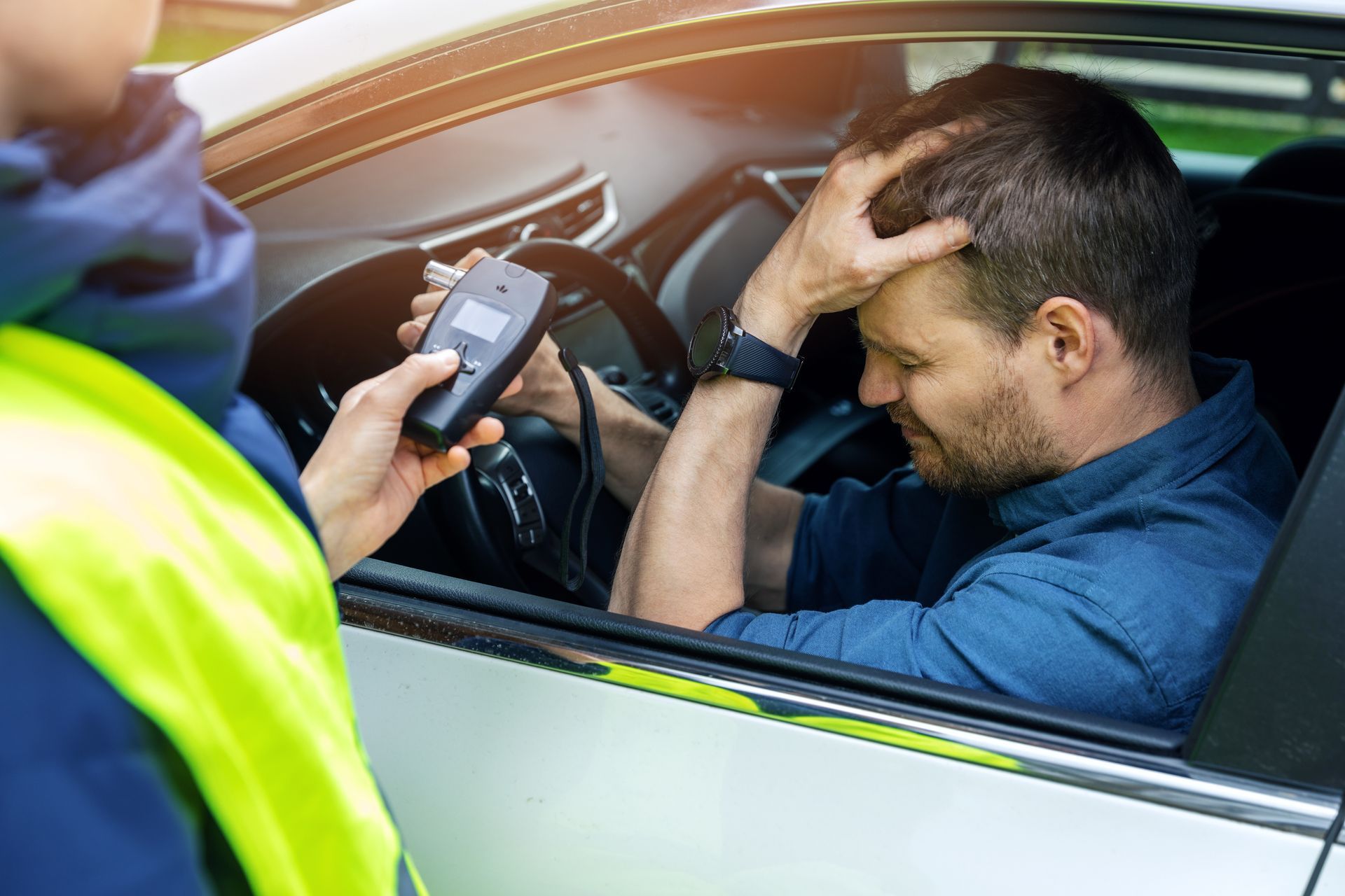 Beamter am offenen Fenster eines Autofahrers mit Alkoholtester