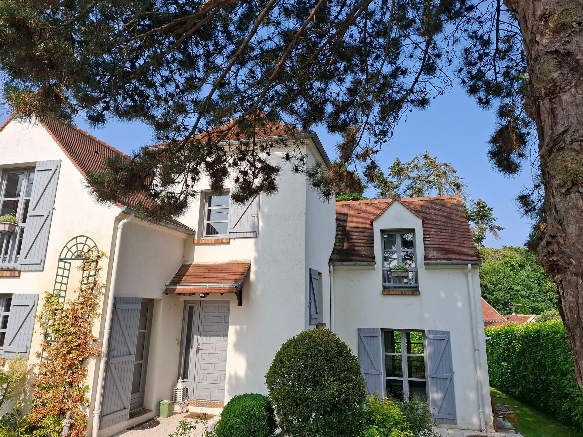 Une grande maison derrière un arbre