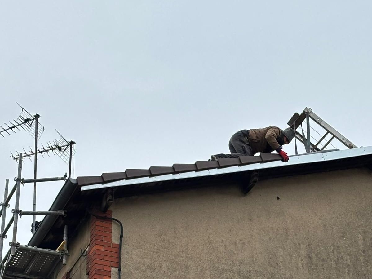 Un homme sur un toit pose des tuiles
