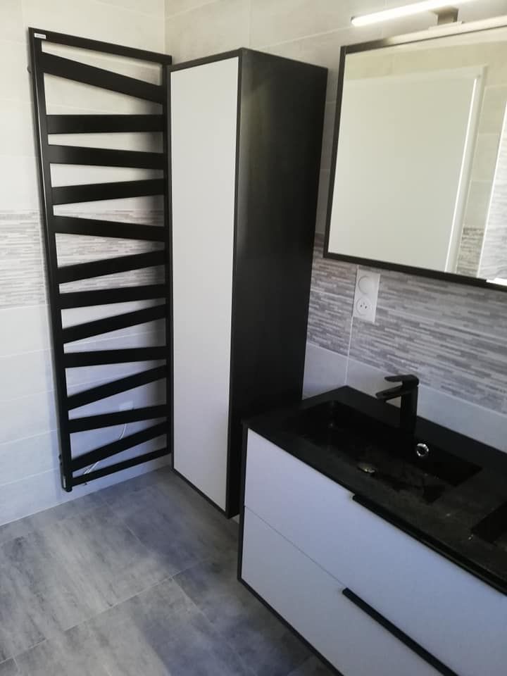 Salle de bains noire et blanche avec porte-serviettes chauffant, armoire, lavabo et miroir.
