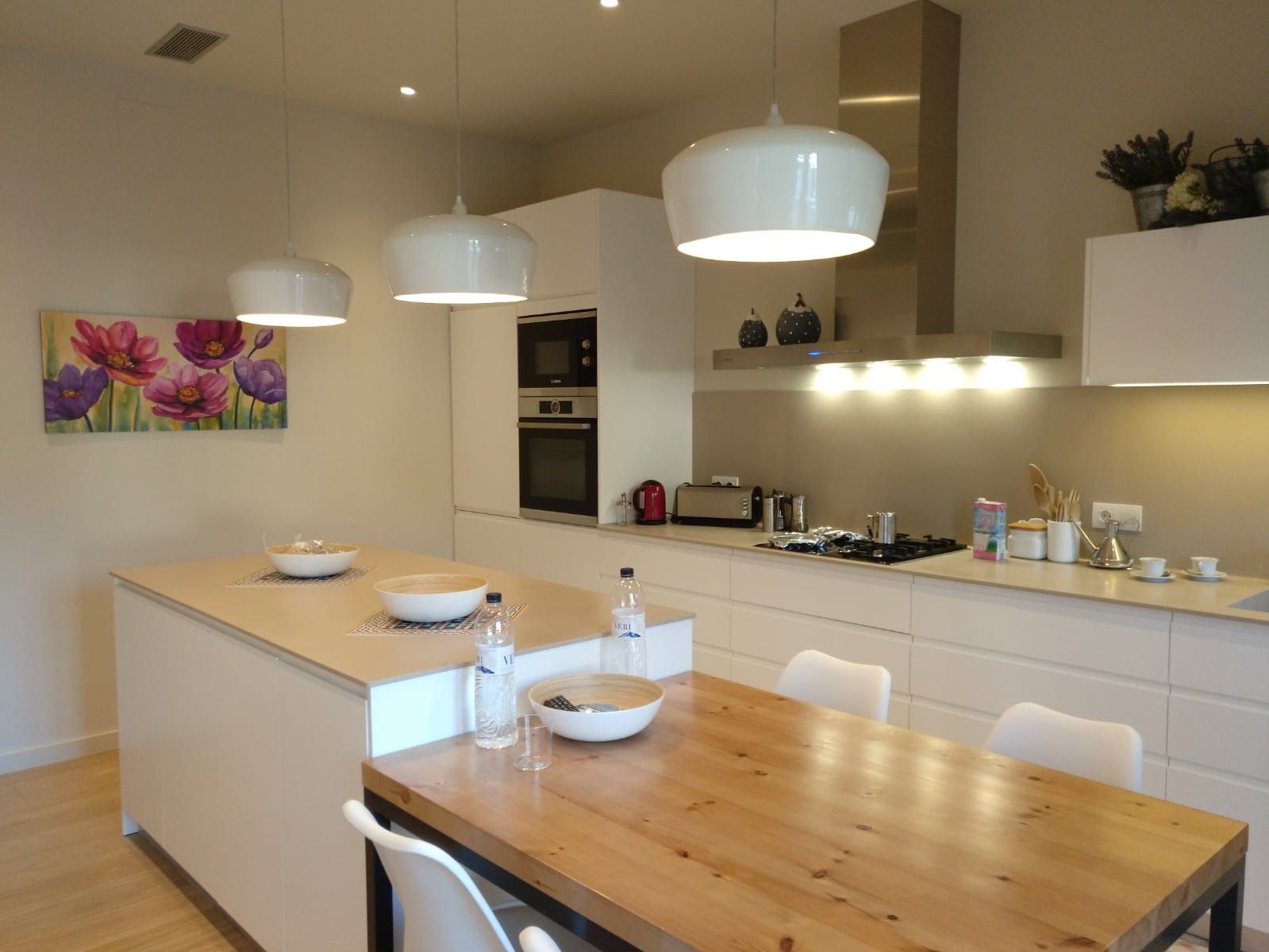 Una cocina con gabinetes blancos y una mesa de madera.