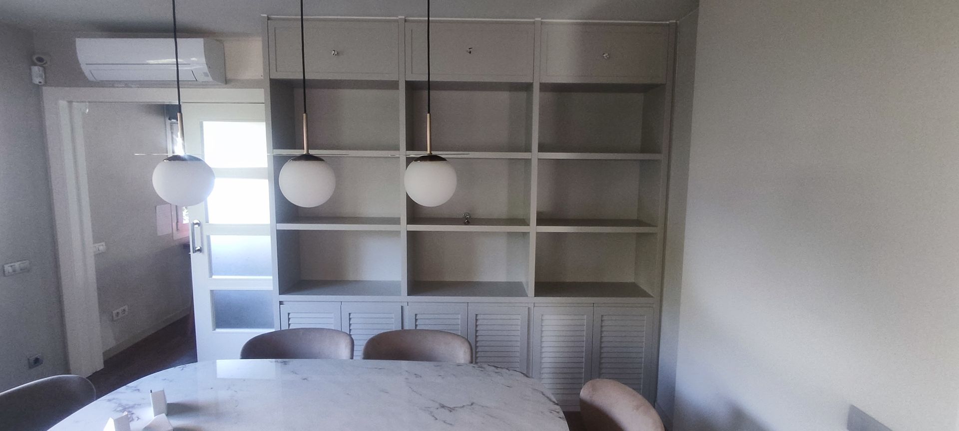 Un comedor con mesa, sillas y estantes.