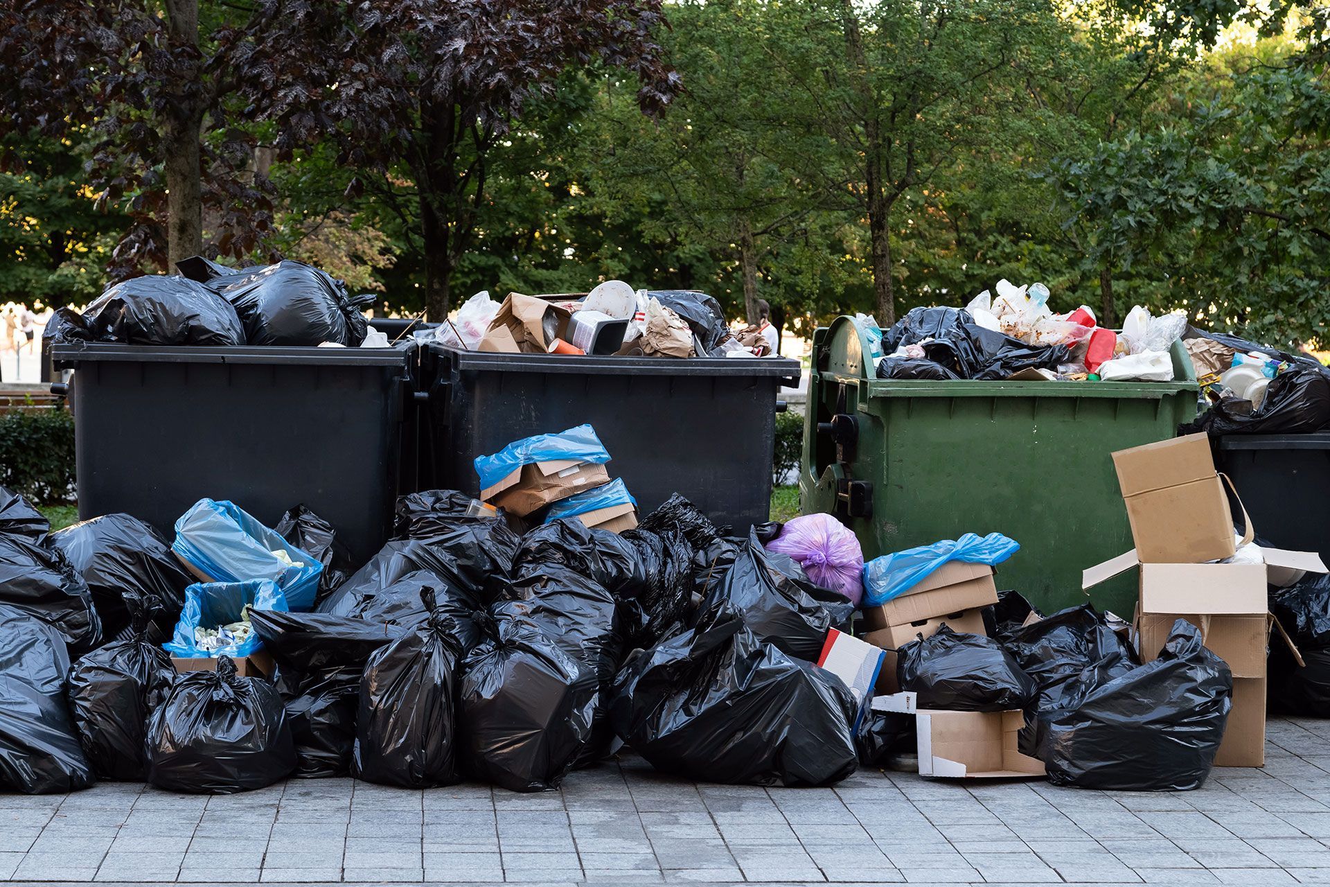 Ein Stapel Müllsäcke und Mülltonnen auf dem Bürgersteig.