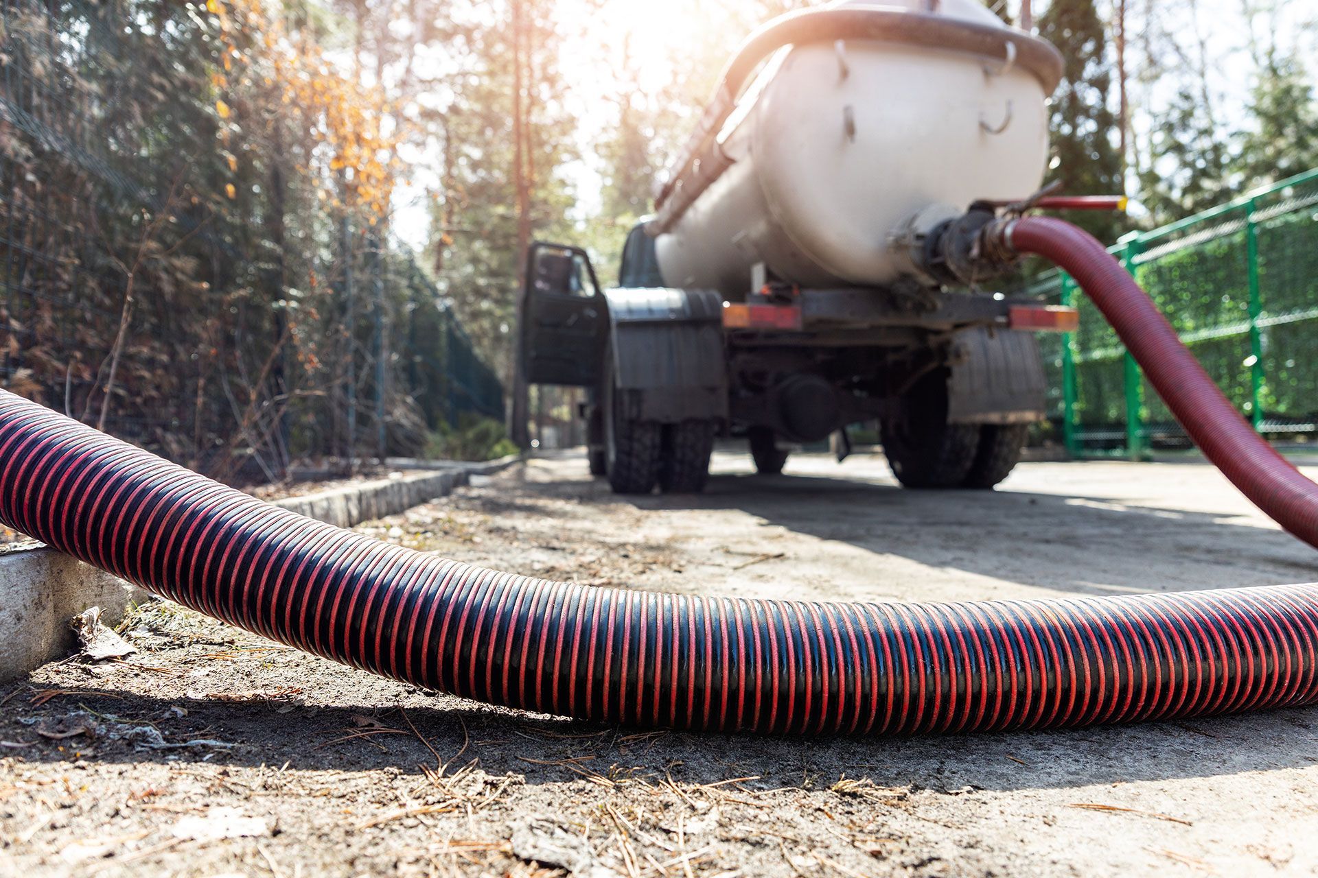 Ein Saugwagen pumpt Wasser mit einem daran angeschlossenen Schlauch in einen Abfluss.