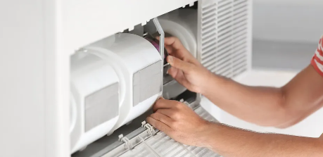 Las manos de una persona están dentro de un electrodoméstico blanco. Están trabajando en una parte del mismo.