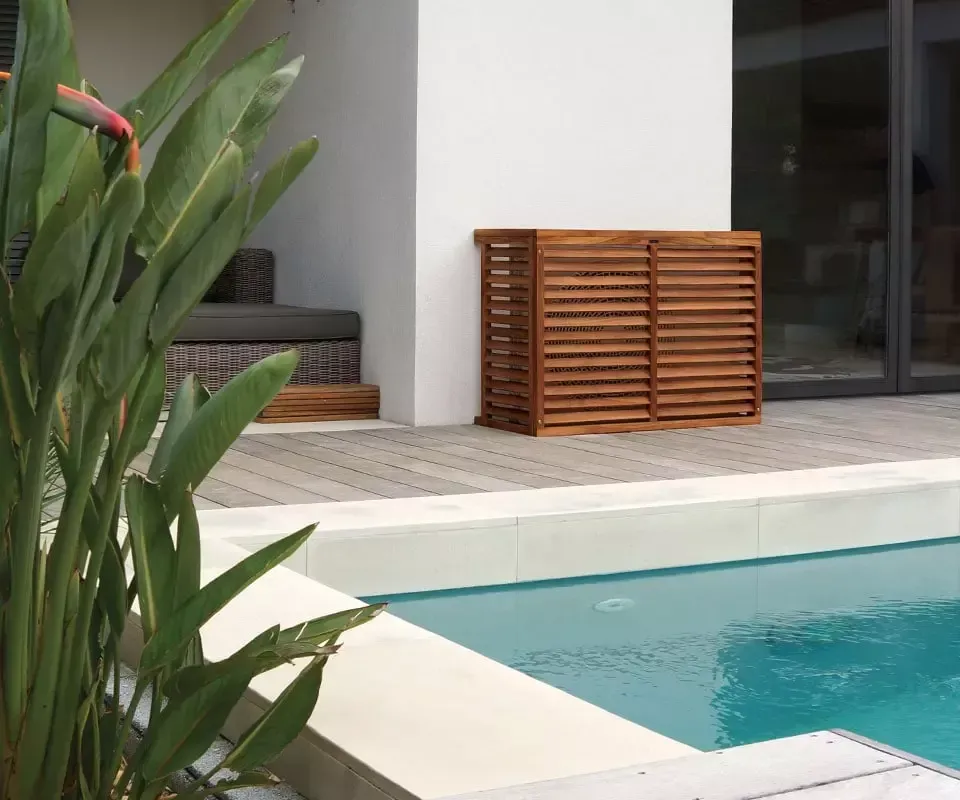 Pompe à chaleur près d'une piscine protégée derrière un cache en bois