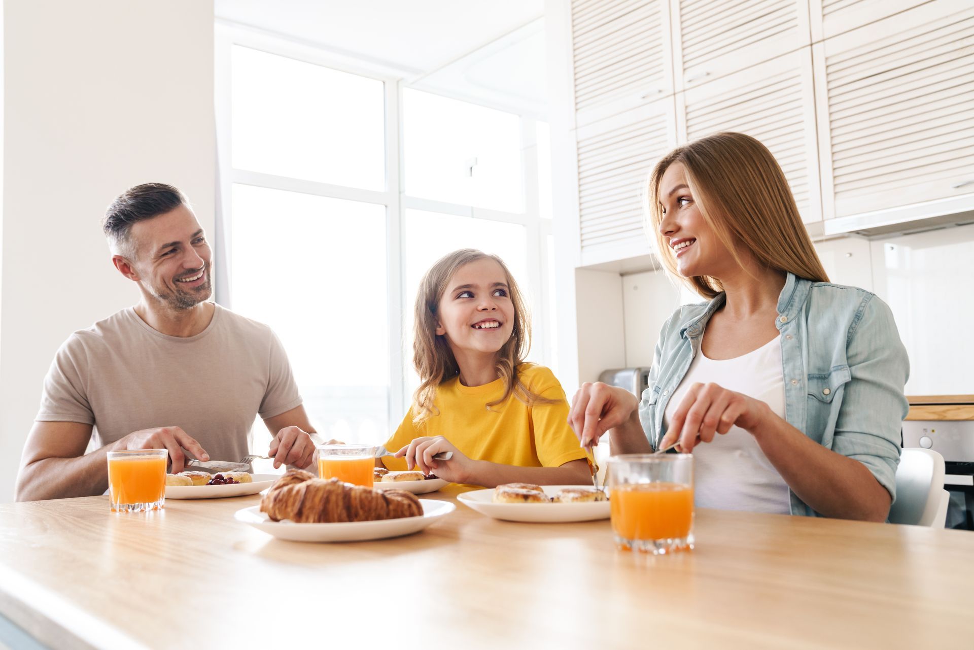 Famille heureuse d'un couple avec un enfant prenant un petit-déjeuner