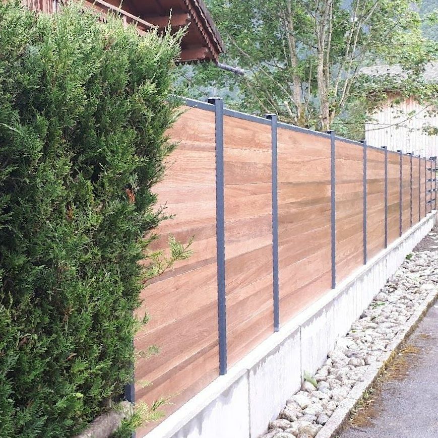 Une clôture en bois avec un muret en béton