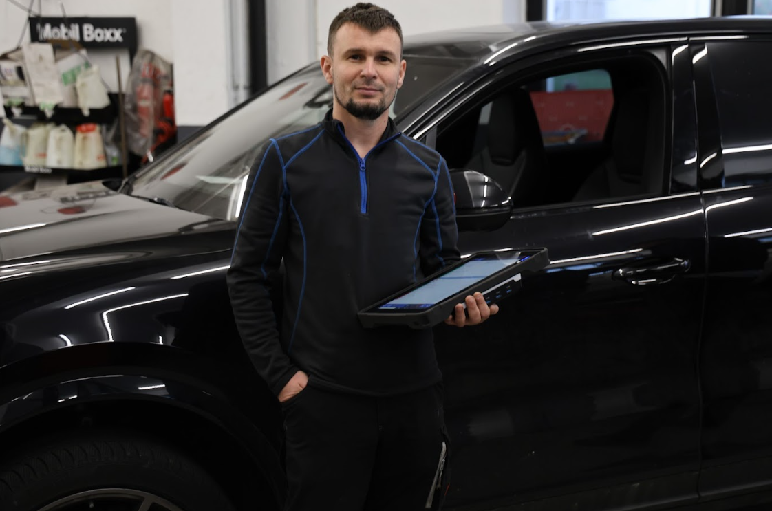 Der Reifen eines schwarzen Sportwagens dreht durch und erzeugt Rauch auf einer Betonoberfläche.