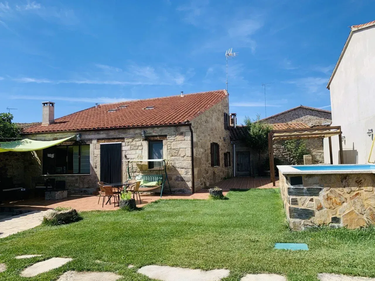 Una casa con techo de tejas rojas y un gran jardín delante de ella.