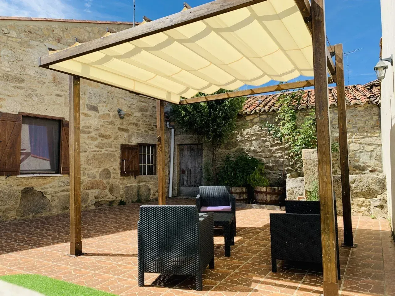 Un patio con pérgola y una piscina al fondo.
