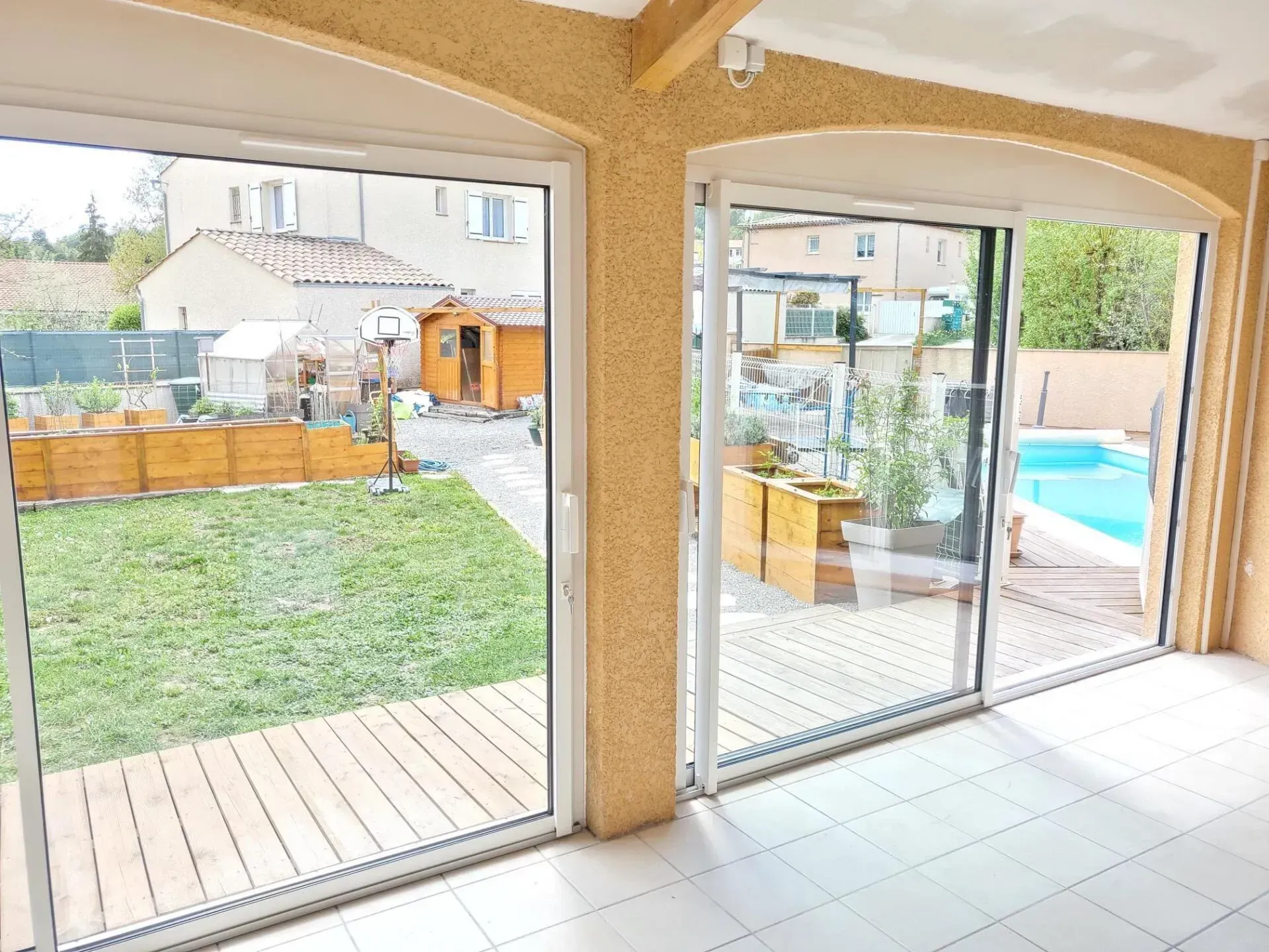 Vue intérieure avec portes coulissantes en verre donnant sur le jardin et la piscine