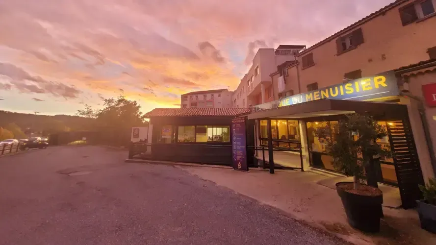 Façade de La Boutique du Menuisier sous un coucher de soleil