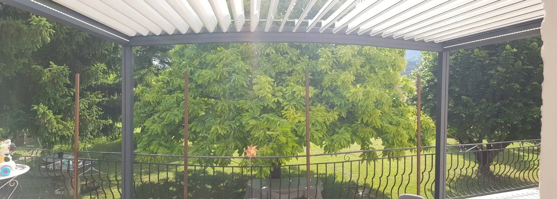 Vue d'un jardin verdoyant depuis l'abri d'une terrasse.