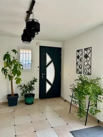 Entrée avec une porte bleu sarcelle foncé, des plantes d'intérieur et un luminaire à lumière noire.