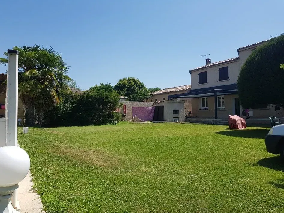 Jardin verdoyant et luxuriant avec une maison en arrière-plan par une journée ensoleillée.