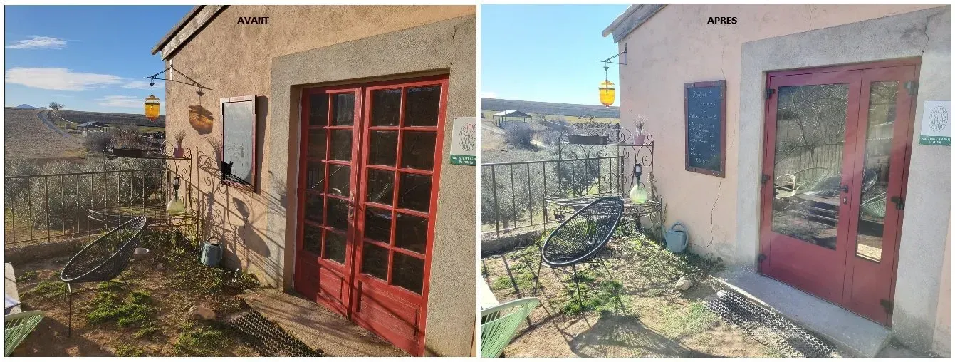 Vue extérieure d'un bâtiment avec des portes rouges, une fenêtre et une enseigne, situé dans un paysage rural.