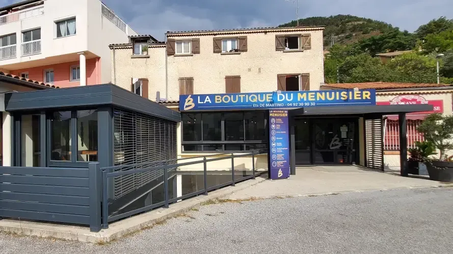 Extérieur de la façade de « La Boutique du Menuisier » avec une terrasse.