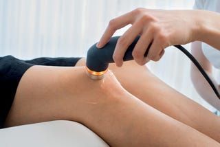 Eine Person genießt eine Hot-Stone-Massage, während sie in einer hellen, ruhigen Umgebung auf einer Liege liegt.