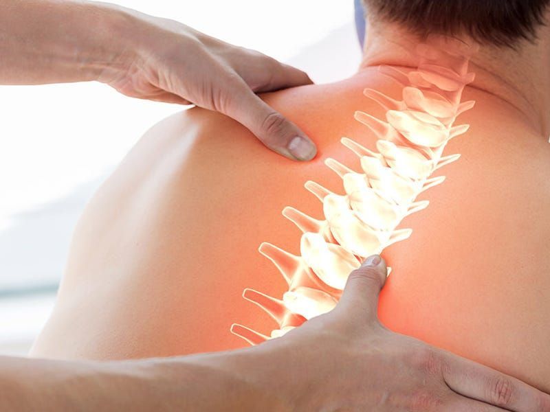 Eine Massagetherapeutin führt eine Fussreflexzonenmassage bei einem Klienten durch, der auf einer Liege mit einem weissen Handtuch ruht.