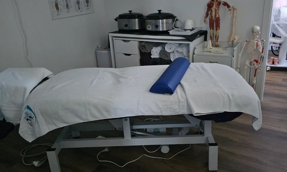 Ein Paar Hände massieren die Füße einer Person, die auf einem weißen Handtuch ruht.