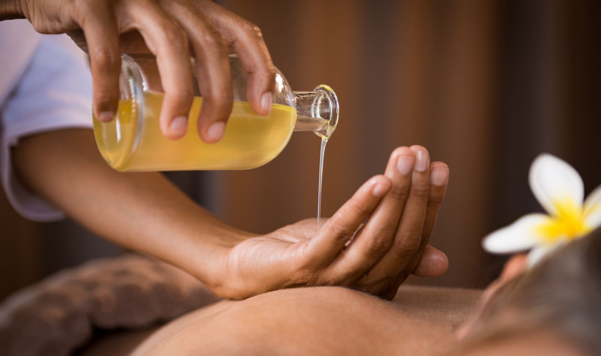 Eine Person genießt eine Hot-Stone-Massage, während sie in einer hellen, ruhigen Umgebung auf einer Liege liegt.