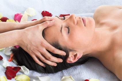 Ein Massagetherapieraum mit Behandlungsliege, blauem Kissen, zwei Wärmetöpfen und einem anatomischen Skelettmodell.