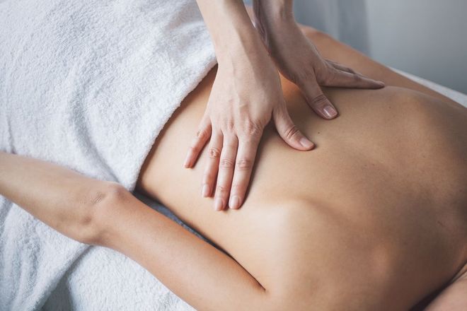 Eine Person, die auf dem Bauch liegend auf einer professionellen Massageliege eine Rückenmassage erhält.